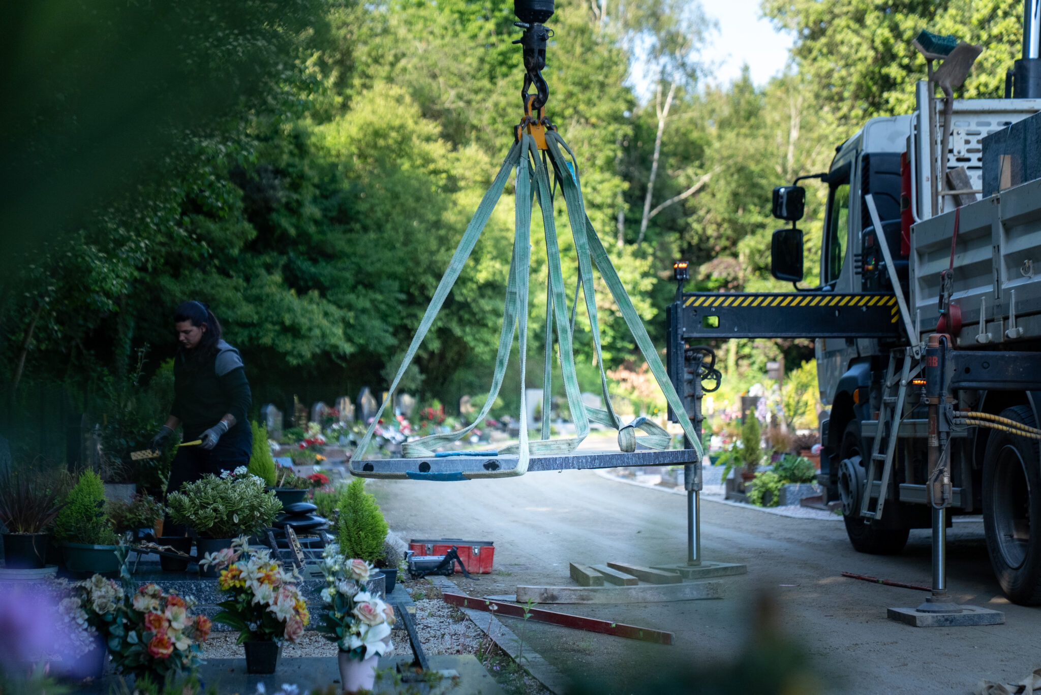 Travail dans un cimetière avec un camion et grue.