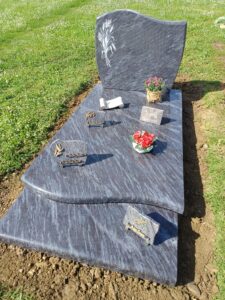 Pierre tombale avec fleurs et décorations.