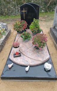 Tombe fleurie avec croix dorée et ornements.