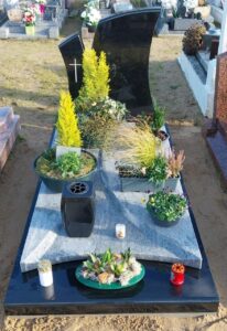 Tombe avec plantes et bougies dans un cimetière.