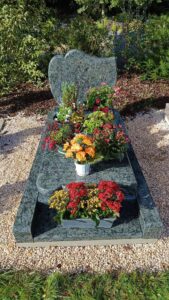 Tombe décorée de fleurs colorées dans un cimetière.