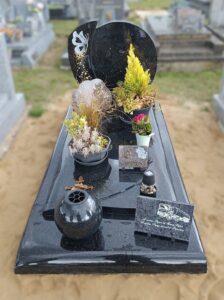 Tombe avec plantes et décorations fleuries.