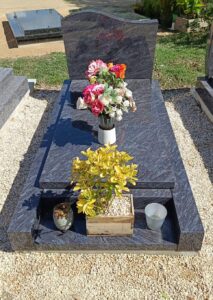 Tombe avec fleurs et plante décorative.