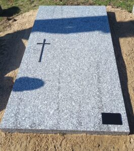 Pierre tombale en granit avec croix métallique.