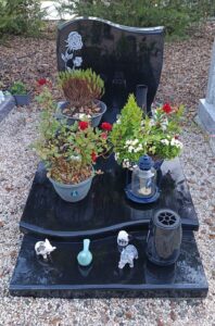 Tombe avec fleurs et lanternes sur pierre noire.