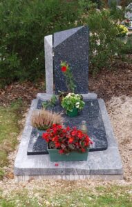 Tombe avec fleurs colorées et pierre tombale grise.