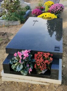 Tombe fleurie avec croix en pierre.