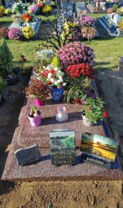 Tombe fleurie avec plaques commémoratives.