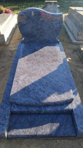 Tombe en pierre grise dans un cimetière.