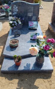 Tombe avec fleurs et plaques commémoratives.