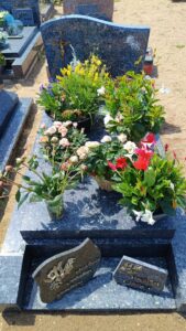 Tombe fleurie avec pierres gravées.