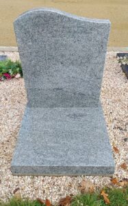 Tombe grise en pierre sur gravier.