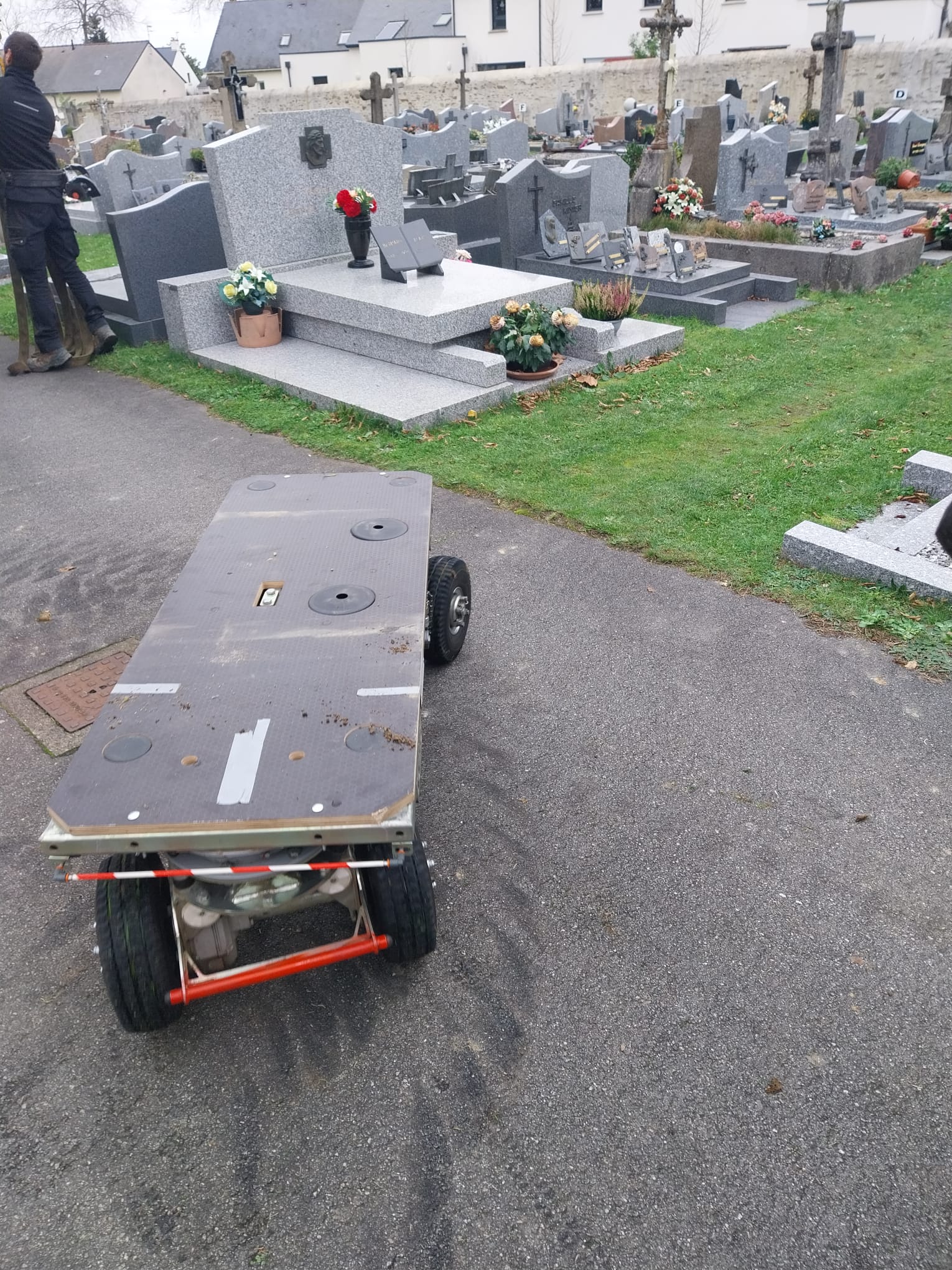 Robot sur roues devant tombes dans un cimetière.